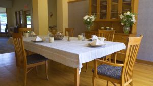 Dining table with chairs and table napkin, mugs and glasses.